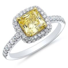 a fancy yellow diamond ring with diamonds around the band and an intricate halo setting in white gold