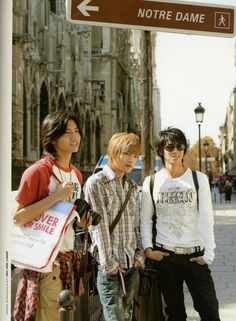 three young men standing next to a street sign