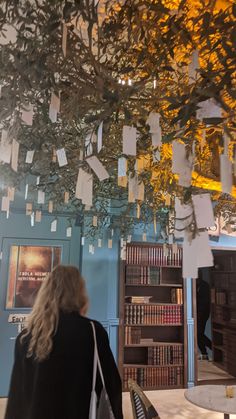 a woman is looking up at a tree with many notes attached to it