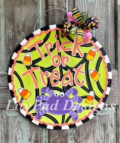 a trick or treat sign hanging on the side of a wooden door with a butterfly