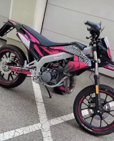 a pink and black dirt bike parked in front of a garage door on the street