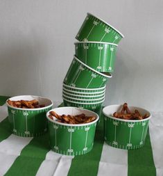 five green bowls filled with food sitting on top of a striped tablecloth covered table