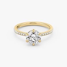 a yellow gold engagement ring with an oval cut diamond and pave set diamonds around the band