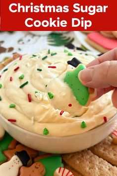 a hand dipping a green christmas sugar cookie dip into a white bowl with sprinkles