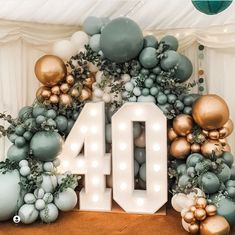 the number forty is displayed in front of balloons and garlands with lights on them