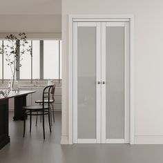 an empty kitchen with white cabinets and black counter tops, along with a dining room table