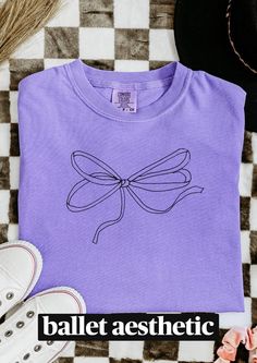 Comfort Colors t-shirt with a cute bow design - a stylish and unique choice Casual chic bow tee - a comfortable and on-trend fashion piece Cute Purple Tops With Relaxed Fit, Purple Cotton Top With Screen Print, Purple Cotton Graphic Tee, Purple Graphic Tee Cotton Top, Cute Long Sleeve Purple T-shirt, Graphic Tee Women, Ballet Aesthetic, Bow Shirt, Comfort Colors Tshirt