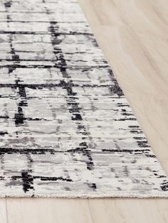 a white and black area rug on a wooden floor with wood floors in the background