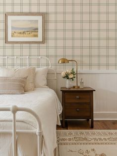 a white bed sitting in a bedroom next to a wooden table with flowers on it