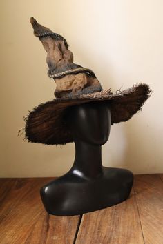 a hat on top of a mannequin's head is sitting on a wooden table