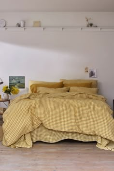 a bed with yellow and white checkered comforter in a room next to a table