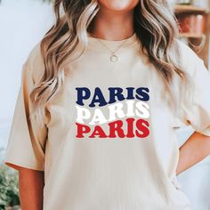 a woman wearing a t - shirt that says paris in red, white and blue