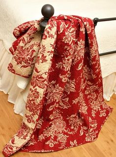 a red and white blanket sitting on top of a bed