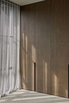 an empty room with wood paneling and sheer curtains