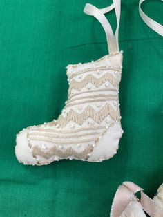 a pair of white shoes sitting on top of a green cloth covered floor next to a christmas ornament