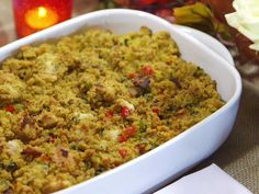 a casserole dish with meat and vegetables in it sitting on a table next to flowers