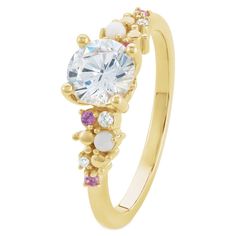 a yellow gold ring with an oval cut diamond surrounded by pink and white stones on the side