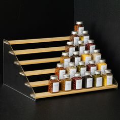 a wooden rack with many jars and spices on the top, in front of a black background