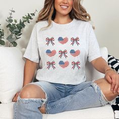 Show your red, white, and blue in adorable style with this trendy American Flag Coquette Tee! This design features a unique twist on a classic symbol, perfect for adding a touch of flirty fun to your wardrobe.  This classic unisex jersey short sleeve tee fits like a well-loved favorite. Soft cotton and quality print make users fall in love with it over and over again. These t-shirts have-ribbed knit collars to bolster shaping. The shoulders have taping for better fit over time. Dual side seams h Trendy Memorial Day Flag Print Tops, Trendy Cotton Tops For Memorial Day, Trendy Short Sleeve Independence Day T-shirt, Trendy Short Sleeve T-shirt For Independence Day, Cute American Flag Print Short Sleeve T-shirt, Cute Short Sleeve Tops For Independence Day, Cute White Tops For Independence Day, Cute Crew Neck T-shirt For Independence Day, Plus Size Summer Fashion