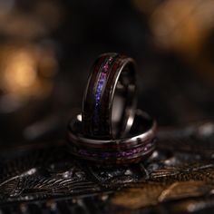 two wedding rings with purple and blue lights on them sitting on top of each other