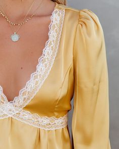 True to Size Self & Lining¨C 100% Polyester Hand Wash Cold. Dry Flat V-Neckline Long Sleeves with Button Cuffs Back Elastic Waistband Lace Trimming Satin-Like Fabrication Back Keyhole with Neckline Button Closure Lined Bust Only Elevate your weekend look in our Lulima Satin Lace Babydoll Blouse! This yellow top features an ivory lace trim. Designed with button cuffs and a v-neckline. Secured with a back button closure. Styled with the Perfect Hoop Earrings. 5 Disc Choker. Chloe Mini Necklace. Ga Off Shoulder Evening Gown, Babydoll Blouse, Simple Bangle, Mini Necklace, Blouse Sale, Mini Skater Dress, Lace Babydoll, Distressed Denim Jacket, Yellow Top