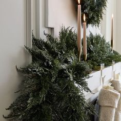 candles are lit on the mantle in front of christmas wreaths