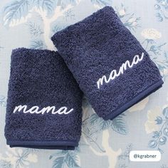 two blue towels with the word mama on them sitting on a floral print tablecloth