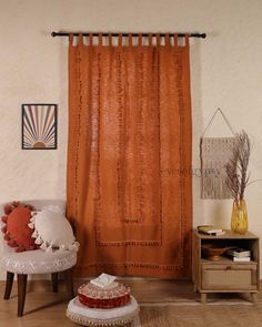 a living room with an orange curtain and white chair