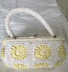 White/yellow bleached woven florals raffia with bead trim 1960's vintage top handle bag is so cute. The bag has an oval shape with a short top handle. The bag has a metal brass frame, with the raffia material wrapped around it. Thick brass kiss lock closure at the top center.  Raffia material is woven into floral patterns. Beads are adorning the flower patterns. The bag opens into a large cotton fabric lined compartment. There's a small pocket inside. The materials this bag is made of; raffia, b Yellow Vintage Bags, Vintage Rectangular Crochet Bag For Vacation, Handmade Vintage Straw Bag, Vintage White Crochet Bag For Summer, Vintage White Rectangular Bag, Vintage Crochet Rectangular Bag For Vacation, White Vintage Rectangular Bag, White Rectangular Vintage Bag, Vintage White Handheld Shoulder Bag