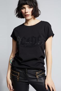 Step into the spotlight in this glittering AC/DC tee. The sleek design features the band's most iconic logo in stunning black crystals that will make you shine like a rock star. Our feminine fitted tee is made with soft cotton fabric, distressed hems, a ribbed crew neckline, and cuffed short sleeves. The design of this style is fitted. For a more standard fit, choose a size up. Details Style #200001 Color: Black Black Crystal AC/DC Logo Fitted T-Shirt Keyword: ACDC 100% Cotton Care/Import Machin Black Embellished Cotton T-shirt, Embellished T-shirt For Night Out, Black Rhinestone T-shirt For Streetwear, Band Logo T-shirt For Concert, Edgy Cotton T-shirt For Night Out, Rocker Style Top For Night Out, Graphic Cotton T-shirt For Night Out, Rhinestone Embellished Short Sleeve T-shirt For Night Out, Graphic Tee Cotton T-shirt For Night Out