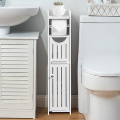 a white cabinet next to a toilet and sink