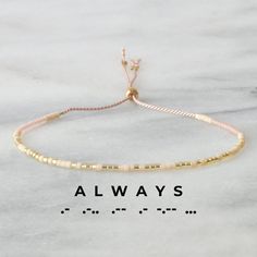 Spread some good vibes and let that special someone know you're always on their mind with this 'ALWAYS' Morse code string bracelet - easily adjustable for a perfect fit. says 'ALWAYS' in Morse Code cream, light gold, and transparent blush glass seed beads on blush silk cord adjustable from 5" - 9" sliding stopper bead makes for an easy-and-off design gold-filled accent crimps won't tarnish all Libby & Smee beaded bracelets come packaged on a logo card in a clear resealing bag for storage and gift giving to keep your jewelry looking new, avoid water, lotions and perfumes Prefer your bracelet to say something else? No problem! Enter a word or phrase — up to 10 letters — in the "message to seller" box at checkout. Meaningful Adjustable Friendship Bracelets, Meaningful Adjustable Friendship Bracelets For Everyday, Inspirational Adjustable Beaded Bracelets For Friendship, Adjustable Inspirational Beaded Bracelets For Friendship, Inspirational Adjustable Gold Friendship Bracelets, Trendy Adjustable Friendship Bracelet, Adjustable Meaningful Bracelets For Friendship, Adjustable Meaningful Bracelet For Friendship, Meaningful Adjustable Friendship Bracelets For Best Friend Gift