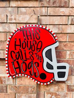 this house calls the hogs football helmet sign on a brick wall in front of a building