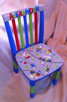 a child's wooden chair with cars and trucks painted on the seat is shown