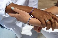 two people holding hands with bracelets on their wrists and one wearing a white shirt