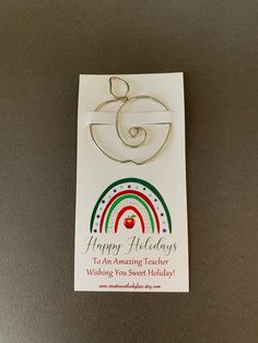 a happy holidays card with an apple hanging from it's side on a table