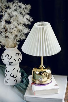 a white lamp sitting on top of a table next to a book