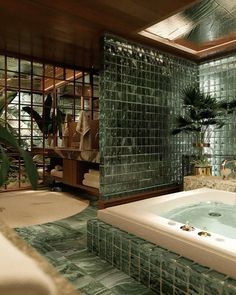 a bath room with a jacuzzi tub surrounded by green tiles and palm trees