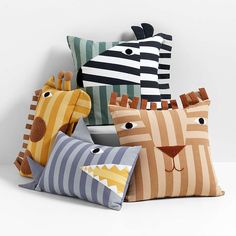 four pillows with different designs on them sitting next to each other in front of a white wall