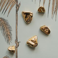 three gold nuggets sitting next to a palm tree