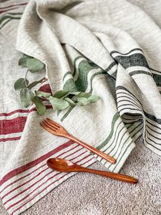 a wooden fork sitting on top of a table next to a white and red towel