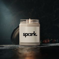 a candle with the word spark on it sitting in front of a black wall and floor