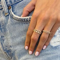 a woman's hand with three diamond rings on her fingers, in jeans pocket