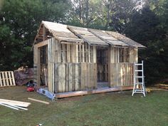 a small wooden shed is being built in the yard with some tools on the ground next to it