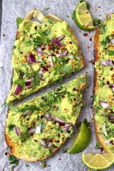 an avocado toast with red onions, cilantro, and lime wedges