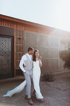 a man and woman standing next to each other in front of a building with doors