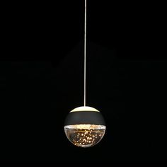 a black and gold colored light hanging from a ceiling fixture in a dark room with the lights turned on