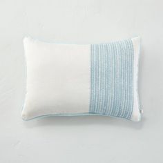 a blue and white striped pillow sitting on top of a white table next to a wall