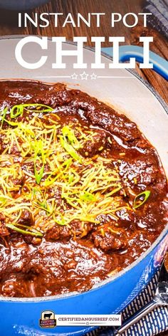 a blue pot filled with chili on top of a wooden table