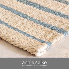 an area rug with blue and white stripes on the bottom, along with text that reads annie selke fine cotton rugs